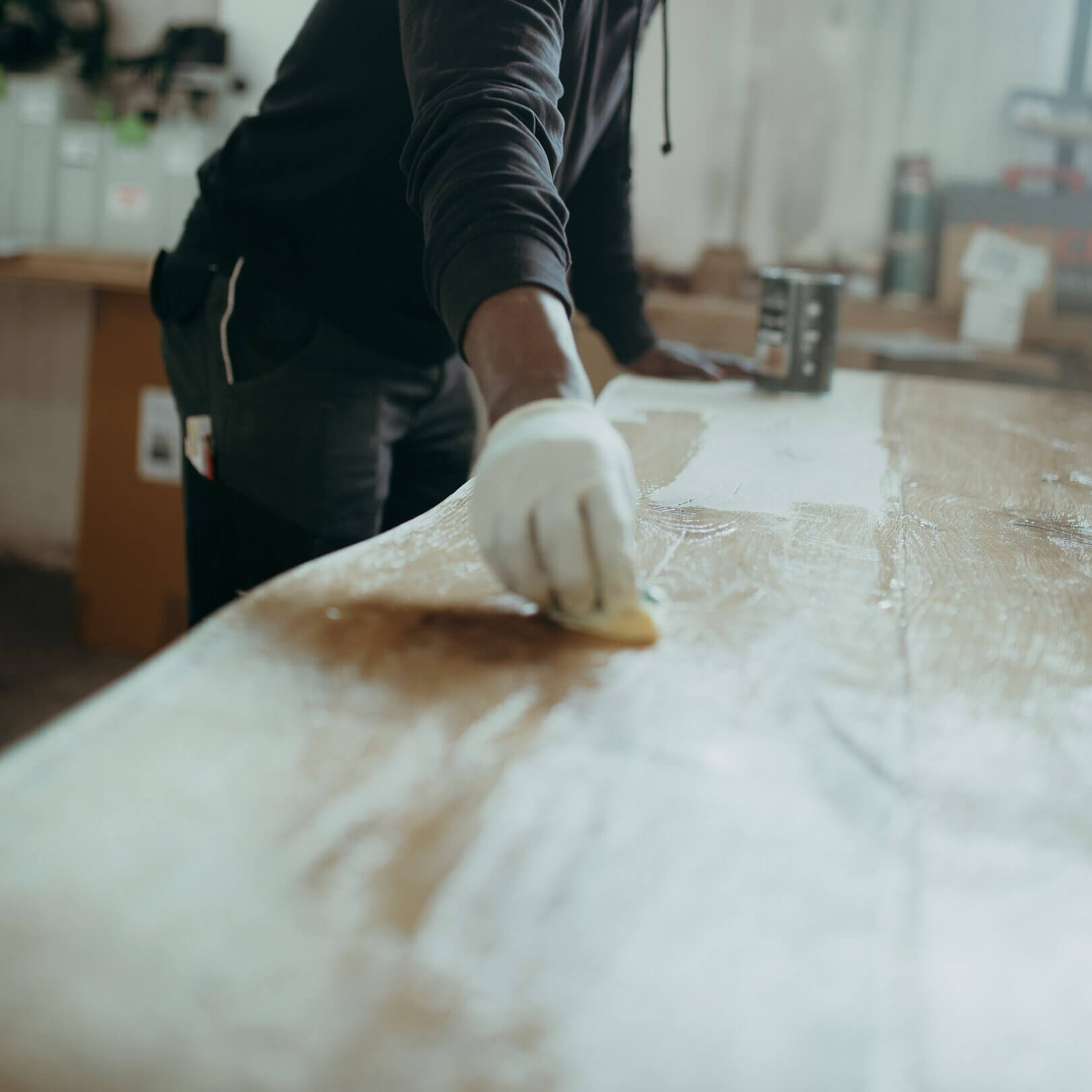 Esstisch aus eiche in werkstatt, mann mit handschuh und lappen, der den tisch einölt, teilweise sichtbar.